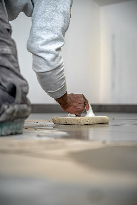 un ouvrier en train d'égaliser le niveau des carreaux de carrelage